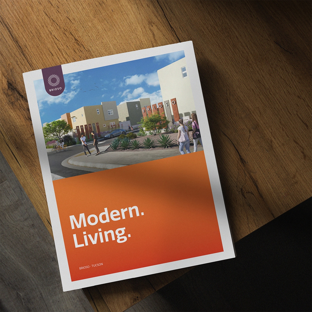 Briso, modern living brochure closed with it's cover shown while situated at the corner of a wooden coffee table.