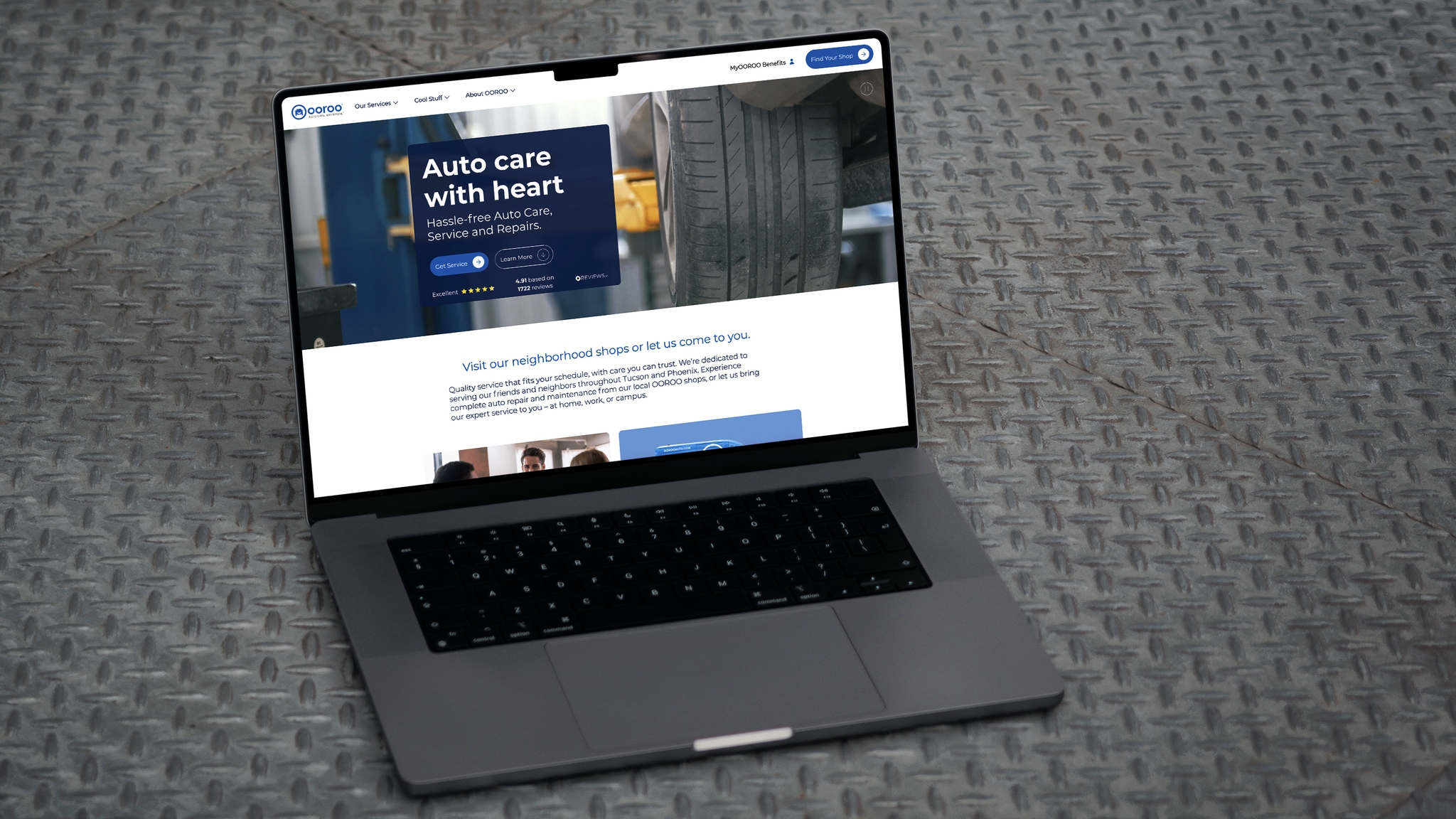 OOROO Auto website homepage displayed on a MacBook pro sat on the floor on metal chequer plate.
